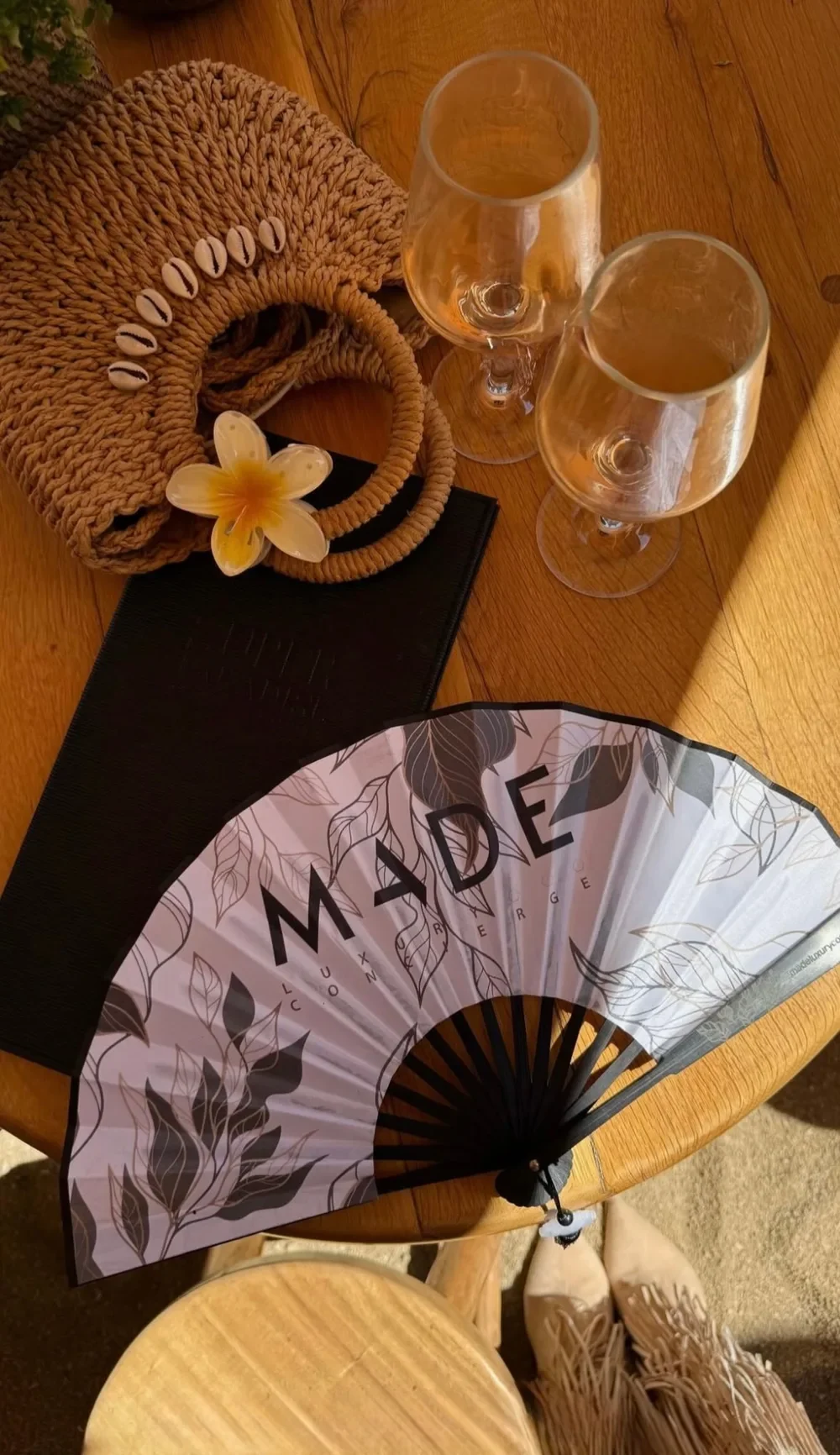 The MADE fan on a beach club table in Mykonos, with two glasses of rosé